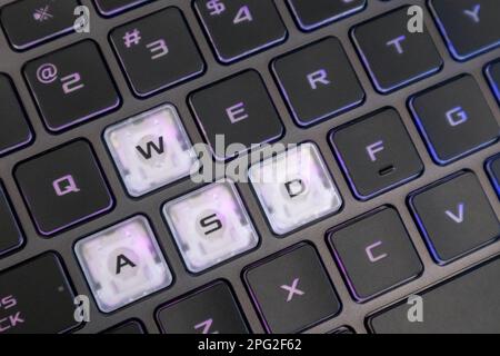 Touches de jeu surlignées avec une lumière de dégradé violette. Gros plan sur un clavier noir puissant pour ordinateur portable. Technologie, INFORMATIQUE, e-sport, informatique Banque D'Images