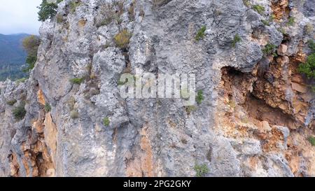 Falaise rocheuse au-dessus de la vallée boisée et de la route de campagne. Vue aérienne des falaises abruptes de montagne. Village de montagne à une distance. Banque D'Images