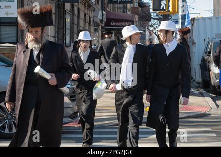Une scène de rue Purim à Brooklyn avec un homme en shtreimal et des garçons en costumes. Banque D'Images