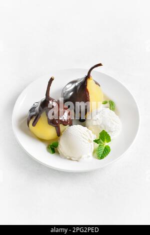 Poires pochées avec sauce au chocolat et crème glacée sur fond blanc avec espace pour les copies. Vue rapprochée Banque D'Images
