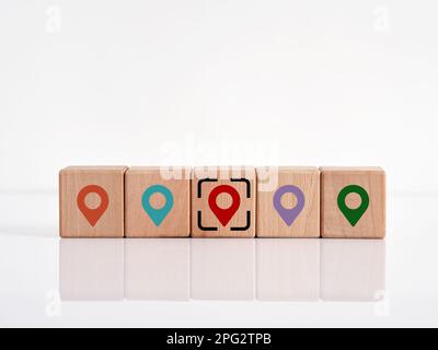 Recherche de l'emplacement ou de la destination cible souhaitée ou appropriée. Symboles d'emplacement des épingles de carte sur les cubes en bois. Gestion logistique. Banque D'Images