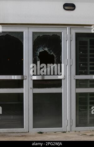 un trou de balle en verre est un trou de balle réel d'une balle de projectile de grand calibre. Porte vitrée percée d'une balle pendant la guerre, attaque terroriste. BR Banque D'Images