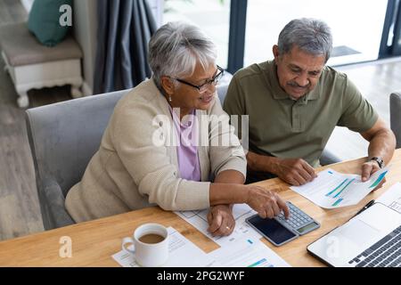 Vue en grand angle du couple biracial senior calculant les dépenses avec les factures sur la table à la maison Banque D'Images