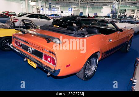 Vue des trois quarts arrière d'un cabriolet Ford Mustang V8 1973, orange et noir, qui fait partie de la vente aux enchères de voitures classiques de Londres 2023 à Olympia, Londres Banque D'Images