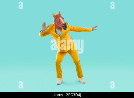 Drôle d'homme dans un masque de cheval drôle et un costume jaune vif. Banque D'Images