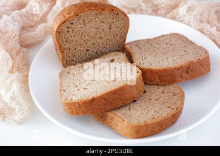 Tranches de pain sans gluten sur une assiette blanche. Gros plan. Banque D'Images