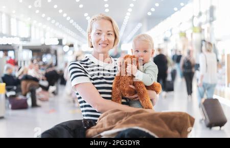 Mère voyageant avec un enfant, tenant son bébé garçon au terminal de l'aéroport attendant de monter à bord d'un avion. Concept voyage avec enfants Banque D'Images