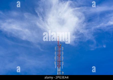 Tour de signalisation radio à ondes de télécommunication rouge et blanc avec ciel nuageux. Armature en acier de l'antenne de signal de transmission avec ciel bleu. Tour de télécommunication Banque D'Images