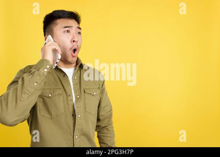 Surpris chinois parlant avec le mobile Banque D'Images