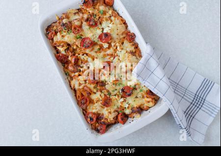 Cocotte de poisson avec saumon, pâtes, tomates, crème et fromage dans un plat de cocotte blanc isolé sur fond blanc Banque D'Images