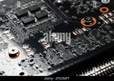 Carte de circuit imprimé noire avec micropuces et condensateurs, macro photo avec mise au point douce sélective Banque D'Images