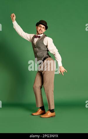 Portrait complet d'un jeune homme beau en vêtements classiques posant, dansant sur fond vert de studio Banque D'Images