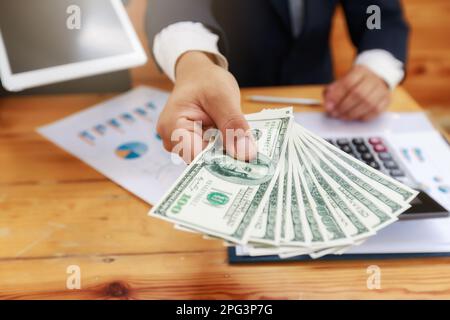 Homme offrant un lot de billets de cent dollars. Homme affichant un écart d'argent. Banque D'Images