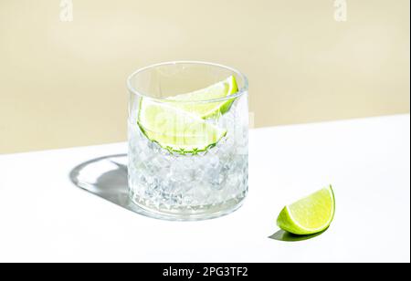 Cocktail alcoolisé TI punch avec rhum blanc, sirop de sucre et citron vert, boisson traditionnelle des Caraïbes. Arrière-plan beige, style minimaliste Banque D'Images