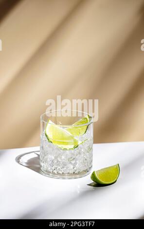 Cocktail alcoolisé TI punch avec rhum blanc, sirop de sucre et citron vert, boisson traditionnelle des Caraïbes. Arrière-plan beige, style minimaliste Banque D'Images