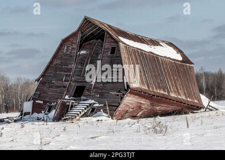 La grange rouge déchue de Dilapuit dans la campagne de la réserve naturelle de Sax-Zim Bog, lors d'une journée d'hiver à Toivola, Minnesota, États-Unis. Banque D'Images