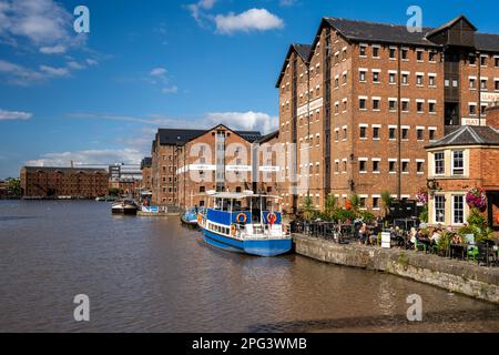 Les gens boivent dans un pub sur les quais régénérés des quais de Gloucester, sous les entrepôts de briques victoriens maintenant convertis en offense résidentielle à usage mixte Banque D'Images