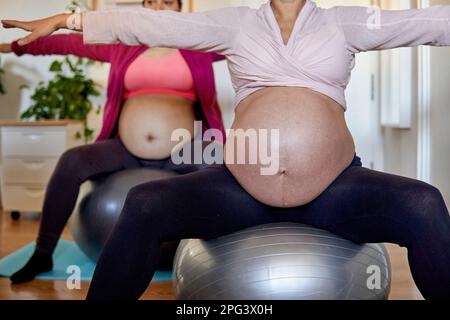 femmes enceintes non reconnaissables faisant du yoga à la maison en utilisant des boules pilates Banque D'Images