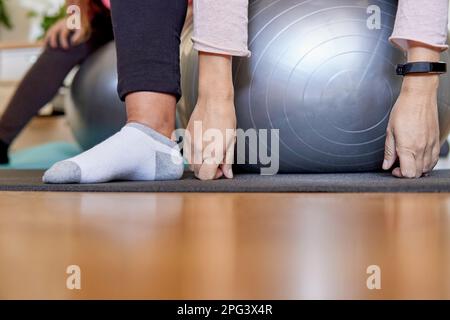 femmes enceintes non reconnaissables faisant du yoga à la maison en utilisant des boules pilates Banque D'Images