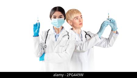 Vaccination contre le coronavirus. Médecins multiethniques féminins tenant des seringues avec vaccin Banque D'Images