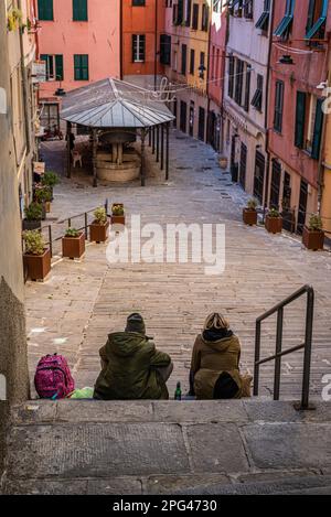 26 février 2022 à Gênes, Italie : le couple est assis tranquillement sur les escaliers anciens en dégustant une bière et en regardant la piazza. Banque D'Images