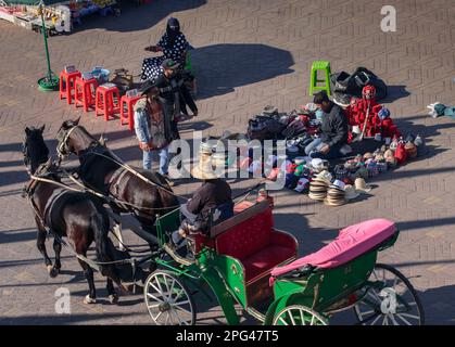 Une calèche passe devant les vendeurs de rue tôt le matin sur la place Gemaa el Fna dans la médina de Marrakech. Banque D'Images