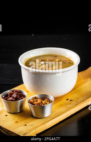 Une planche en bois avec trois bols en céramique remplis de divers noix et un bol de soupe aux champignons Banque D'Images