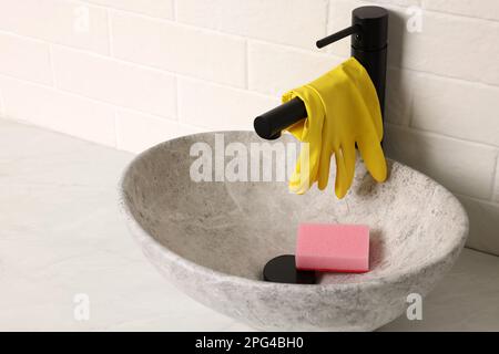 Gants en caoutchouc sur le robinet dans l'évier de la salle de bains Banque D'Images