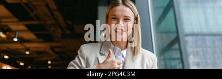 Femme d'affaires souriante communiquant en langage des signes tout en regardant la caméra pendant qu'elle est assise dans un café Banque D'Images