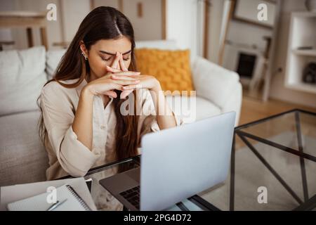 Malheureux fatigué millénaires race mixte femme avec ordinateur portable souffrant de travail excessif, de pression, de migraine et de stress Banque D'Images