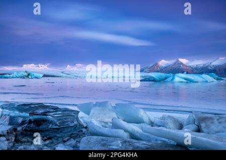 Lever du soleil avec des nuages de glace nacrés colorés au lagon du glacier de Jokulsarlon, en bordure du parc national de Vatnajökull, en Islande Banque D'Images