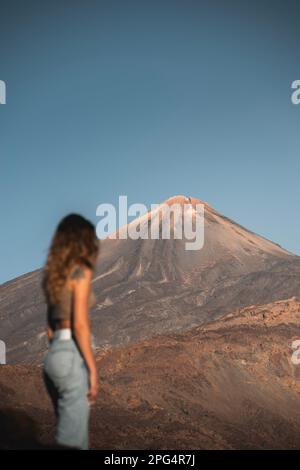 Chica pas de reconnaissance paseando por el parque nacional de las cañadas del Teide al atardecer. El pico Teide al fondo. Banque D'Images