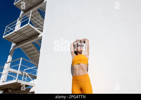 Femme sportive faisant un bras extensible exercices d'échauffement à l'extérieur au soleil Banque D'Images