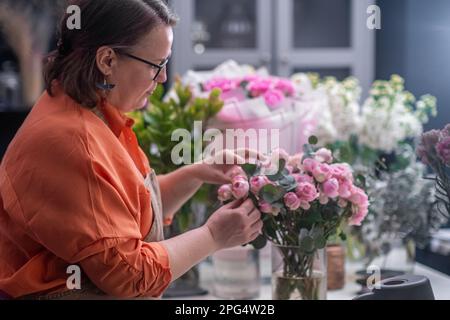 la fleuriste féminine prépare avec art un magnifique bouquet de fleurs de printemps, travaillant à son magasin de fleurs Banque D'Images