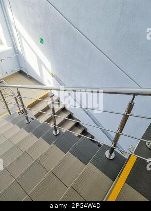 Escalier moderne en métal.vue vers le bas à un escalier moderne avec mur blanc comme se trouve dans un bureau, un hôpital ou un appartement.jour ensoleillé.ligne jaune Banque D'Images
