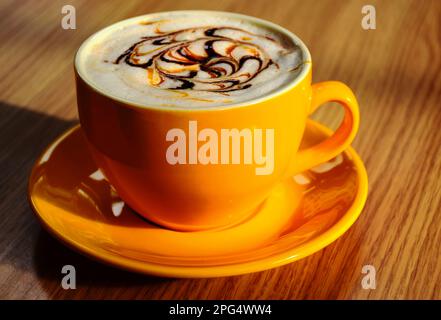 tasse à cappuccino ou tasse en porcelaine jaune avec vue rapprochée. surface réfléchissante brillante. mousse blanche décorative. motif chocolat. concept de café chaud savoureux. Banque D'Images
