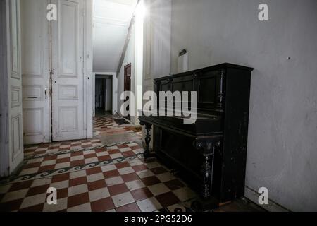 Vieux piano sur sol carrelé dans un bâtiment abandonné Banque D'Images