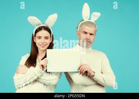 Le couple de Pâques tient un tableau blanc vierge pour votre texte. Banque D'Images