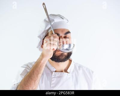 Jeune chef masculin utilisant une louche en métal. Isolé sur un fond blanc Banque D'Images