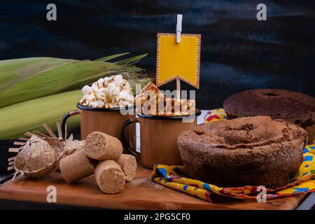 drapeau en papier, gâteau, pop-corn et bonbons de festa junina sur table en bois noir. Banque D'Images