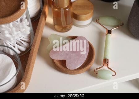 Outils Gua sha, rouleau à cadran naturel et produits de toilette sur étagère blanche Banque D'Images