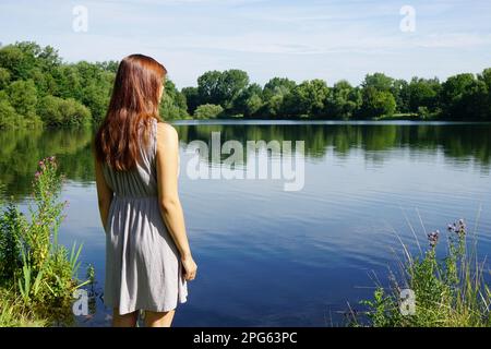 Vue arrière de jeune femme à la recherche sur le lac idyllique avec copie espace Banque D'Images