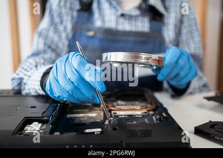 Femme ingénieur réparant et modernisez l'ordinateur portable dans le centre de service. Utilisez des outils. Matériel informatique. Loupe. Ordinateur portable démonté Banque D'Images
