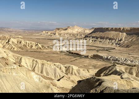 En regardant vers le bas sur le ruisseau nahal wadi Zin qui serpente à travers la vallée de Zin en face de la montagne Hod Akev près de SDE Boker en Israël avec un ciel bleu clair Banque D'Images