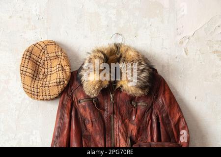 veste en cuir rouge et casquette à carreaux accrochés au vieux mur blanc, mode Banque D'Images