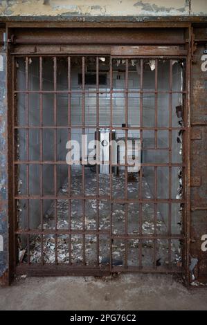 Une vieille cellule de prison en ruine avec une porte cassée et des toilettes en arrière-plan Banque D'Images