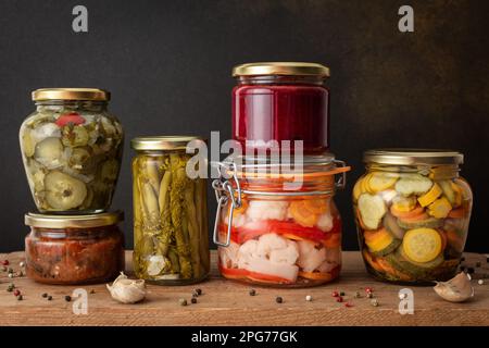 Conservation des légumes pour l'hiver, légumes en conserve en pots sur une table en bois contre un mur brun, légumes marinés ou fermentés, espace de copie Banque D'Images