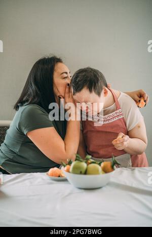Style de vie, éducation. Une femme âgée atteinte du syndrome de Down étudie en cuisine ou en classe avec un enseignant Banque D'Images