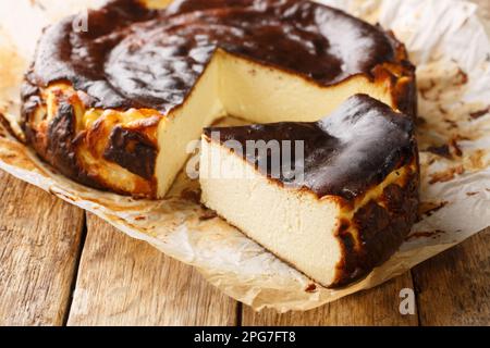Rustiques frais et délicieux cheesecake basque maison à proximité sur le papier parchemin sur la table en bois. Horizontale Banque D'Images