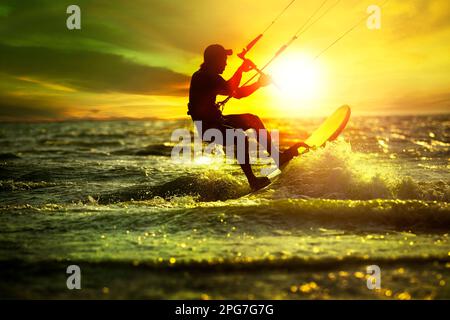 homme jouant du kite surf sur la mer de rushing contre beau coucher de soleil ciel Banque D'Images